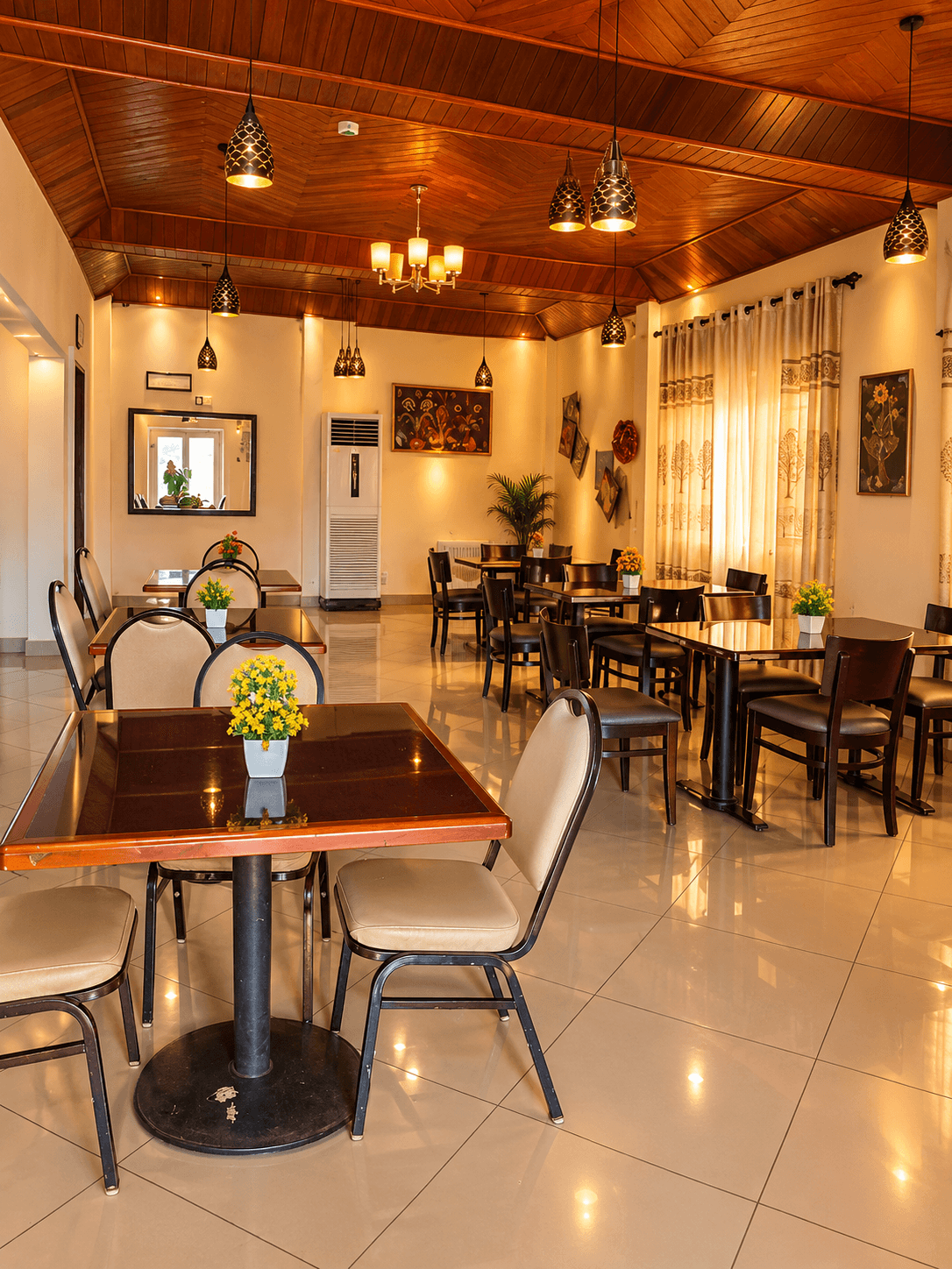 Dining room with leather armchairs set for service beside tall windows and palms