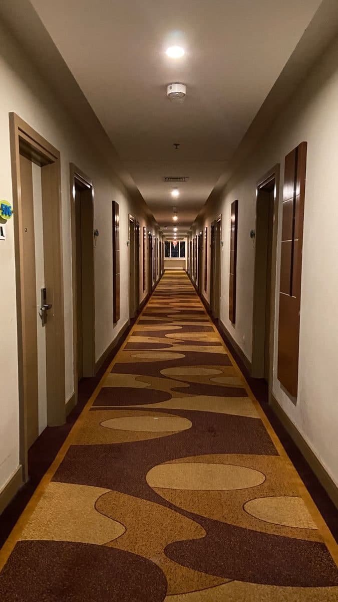 Quiet guest corridor at night, softly lit, with a patterned carpet