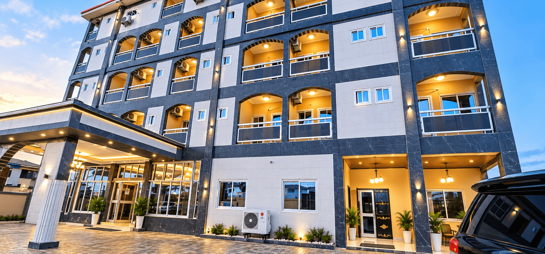 Emmarie Hotel at dusk, its arched balconies lit warmly above the entrance canopy